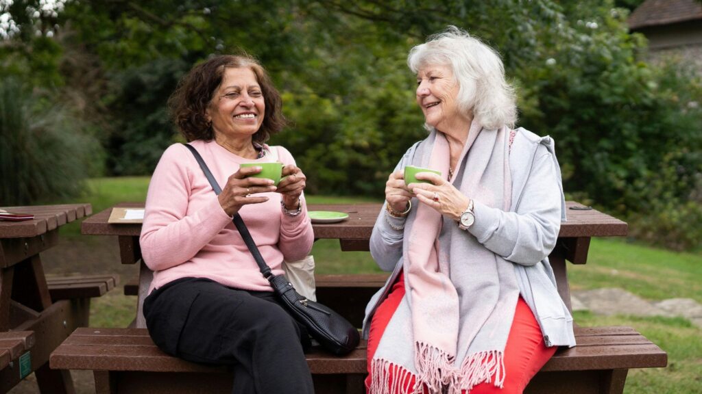 two ladies enjoying tea in the park whilst talking about charity fundraising