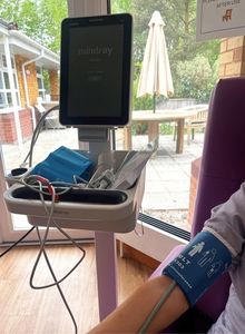 photograph of a Dinamap, to monitor patients’ blood pressure and other vital statistics, machine in use by a patient. The purchase of the machine for Queenscourt Hospice was made possible by funds from Hospice Aid UK
