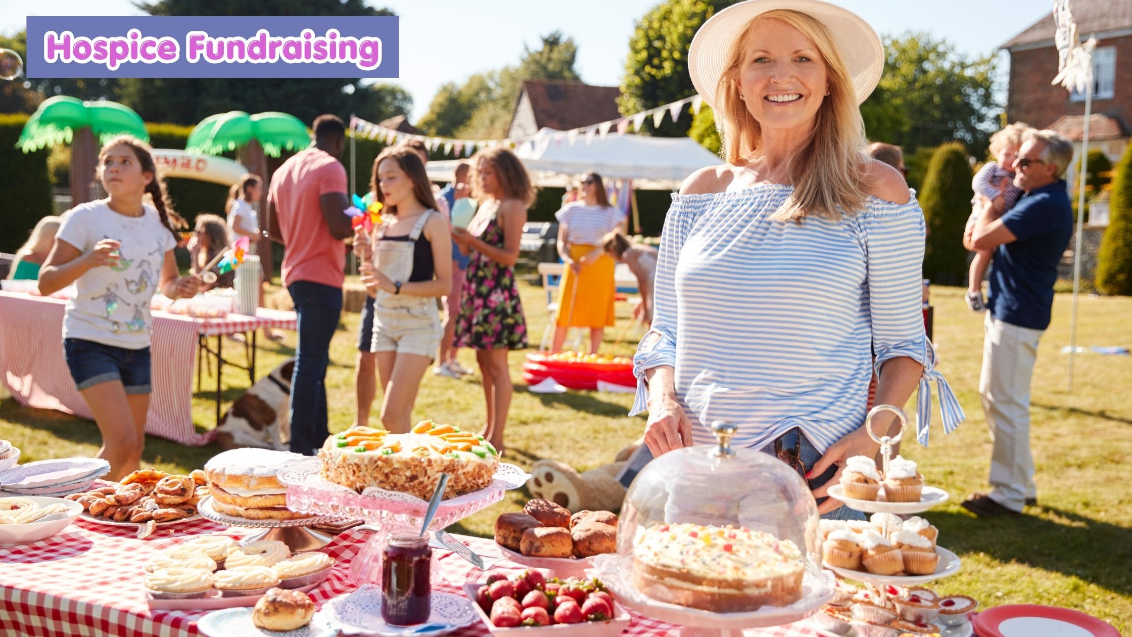 Outdoor summer fundraiser with woman standing behind a cake stall with lots of delicious sweet treats for sale