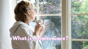 woman in bathrobe holding a cup of tea and gazing out of a window on to a garden with trees