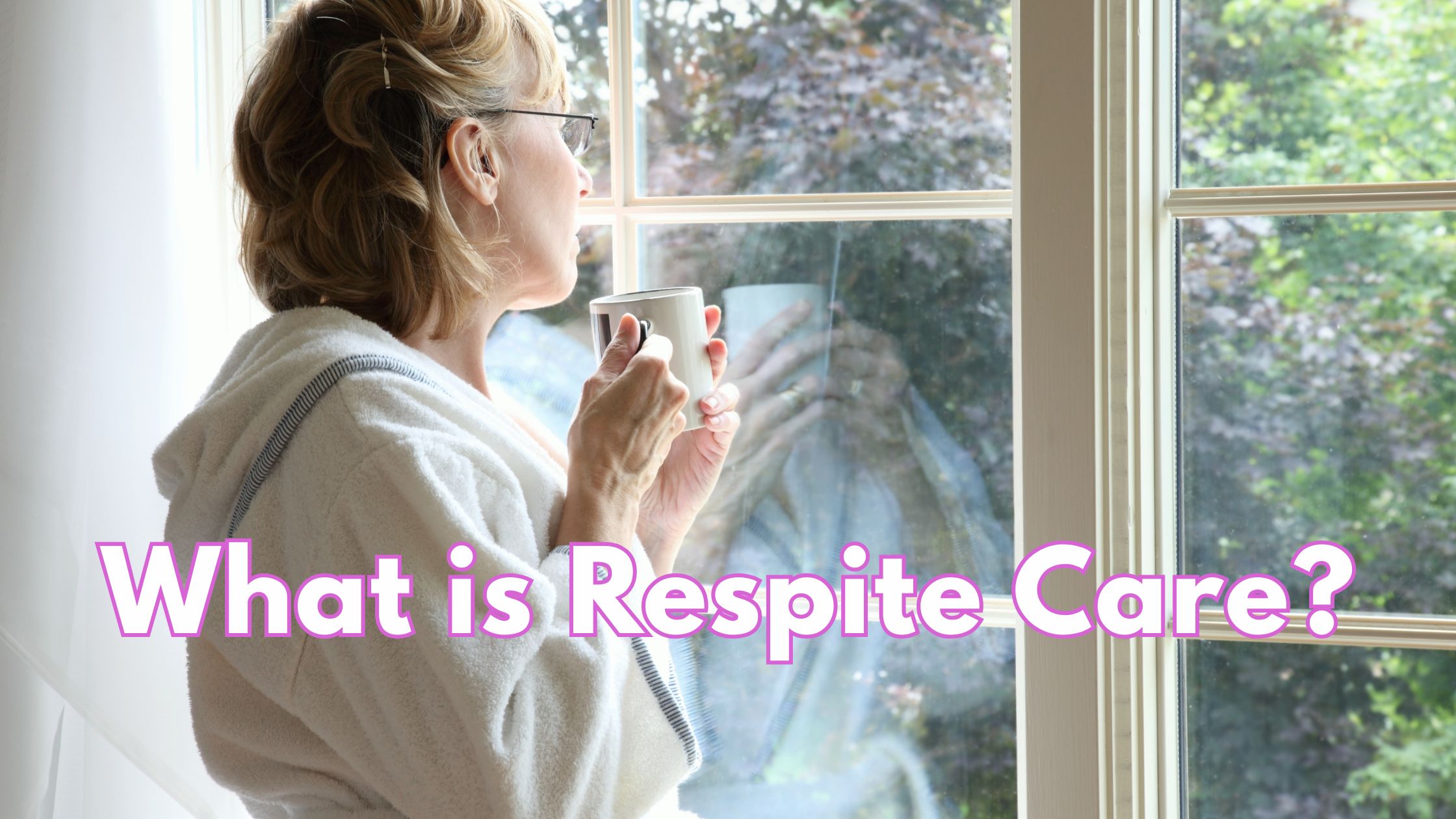 mature woman in bathrobe, holding a cup of tea and gazing out of a window, onto a garden with trees.